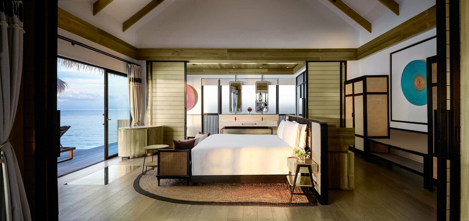 Luxurious bedroom with a modern design, featuring a large bed, wooden accents, and ocean views. Soft lighting and minimalistic decor create a serene ambiance.