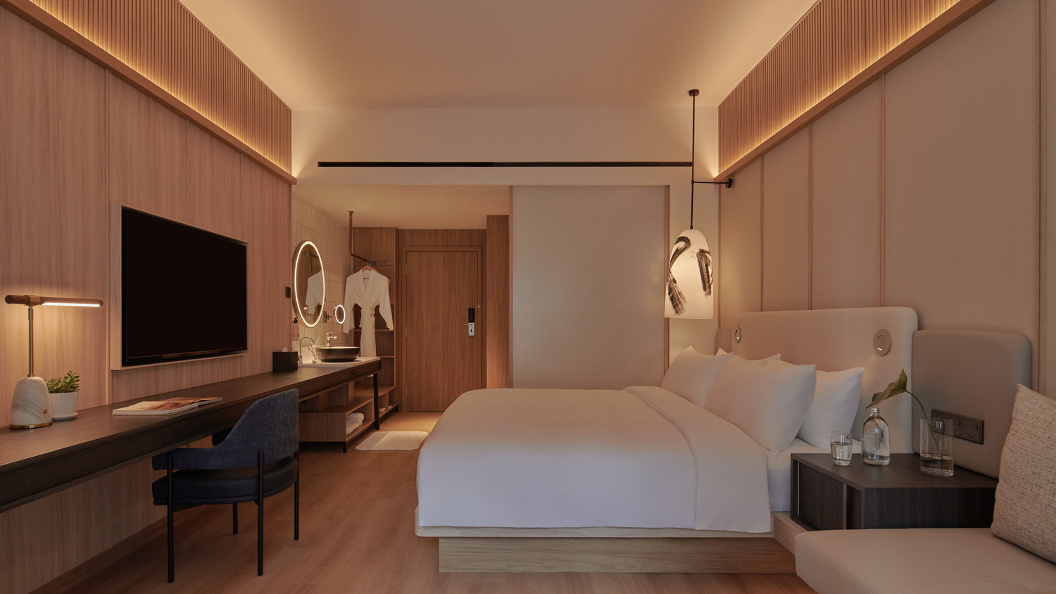 Modern hotel room with warm lighting, featuring a large bed, wall-mounted TV, sleek desk with chair, and minimalist decor. Cozy and inviting atmosphere.