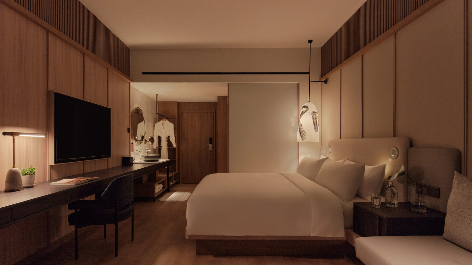 Modern hotel room with warm lighting, featuring a large bed, wall-mounted TV, sleek desk with chair, and minimalist decor. Cozy and inviting atmosphere.
