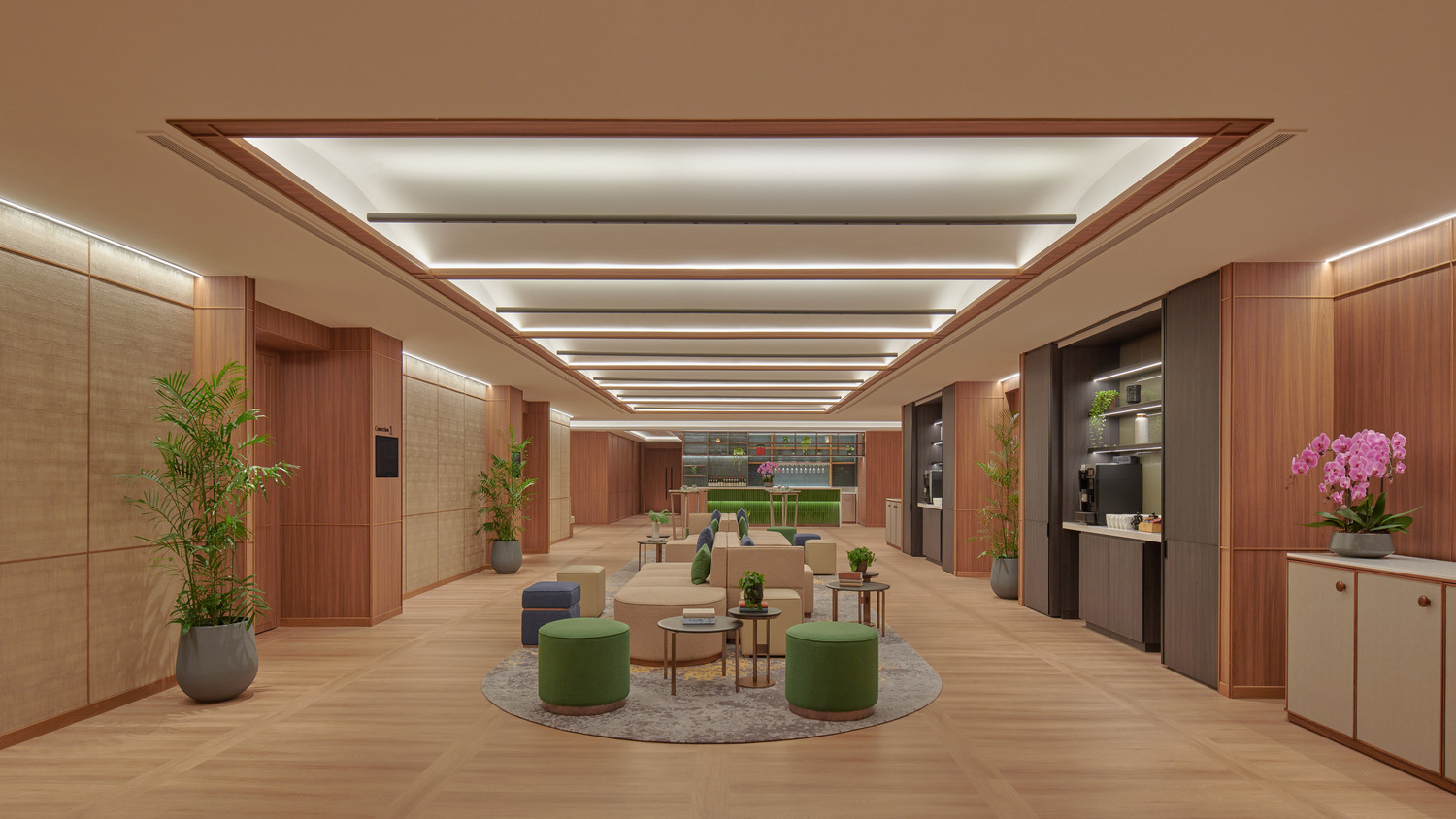 Modern foyer with wooden tones and sleek lighting. Features seating areas with green and blue accents, plants, and a coffee station, creating a welcoming atmosphere.