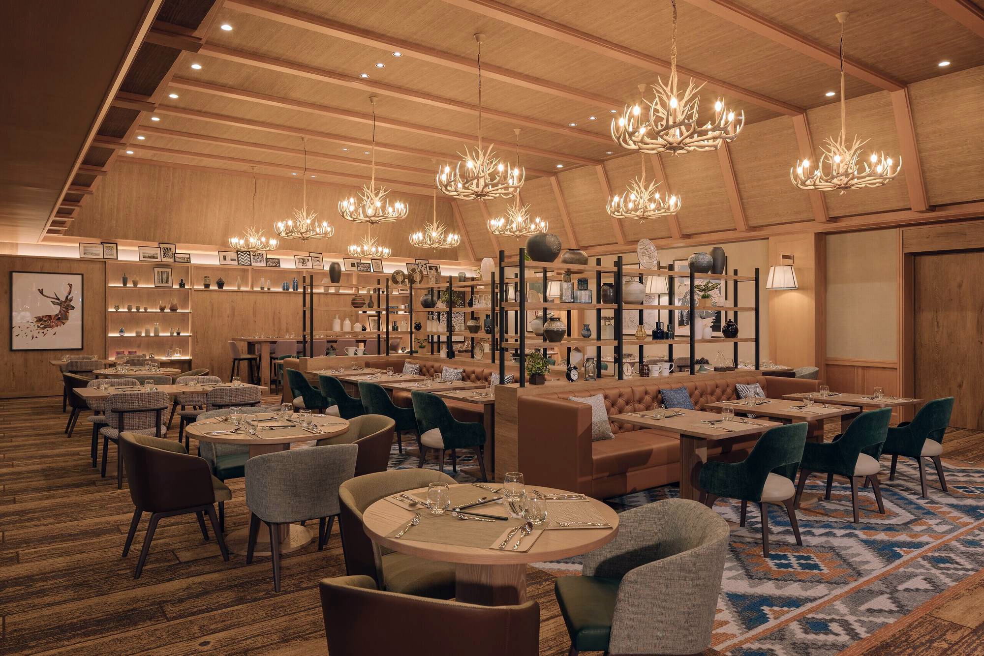 Rustic restaurant interior with warm lighting, featuring round tables set with cutlery, green and brown chairs, chandeliers, and wooden accents. Cozy and elegant atmosphere.