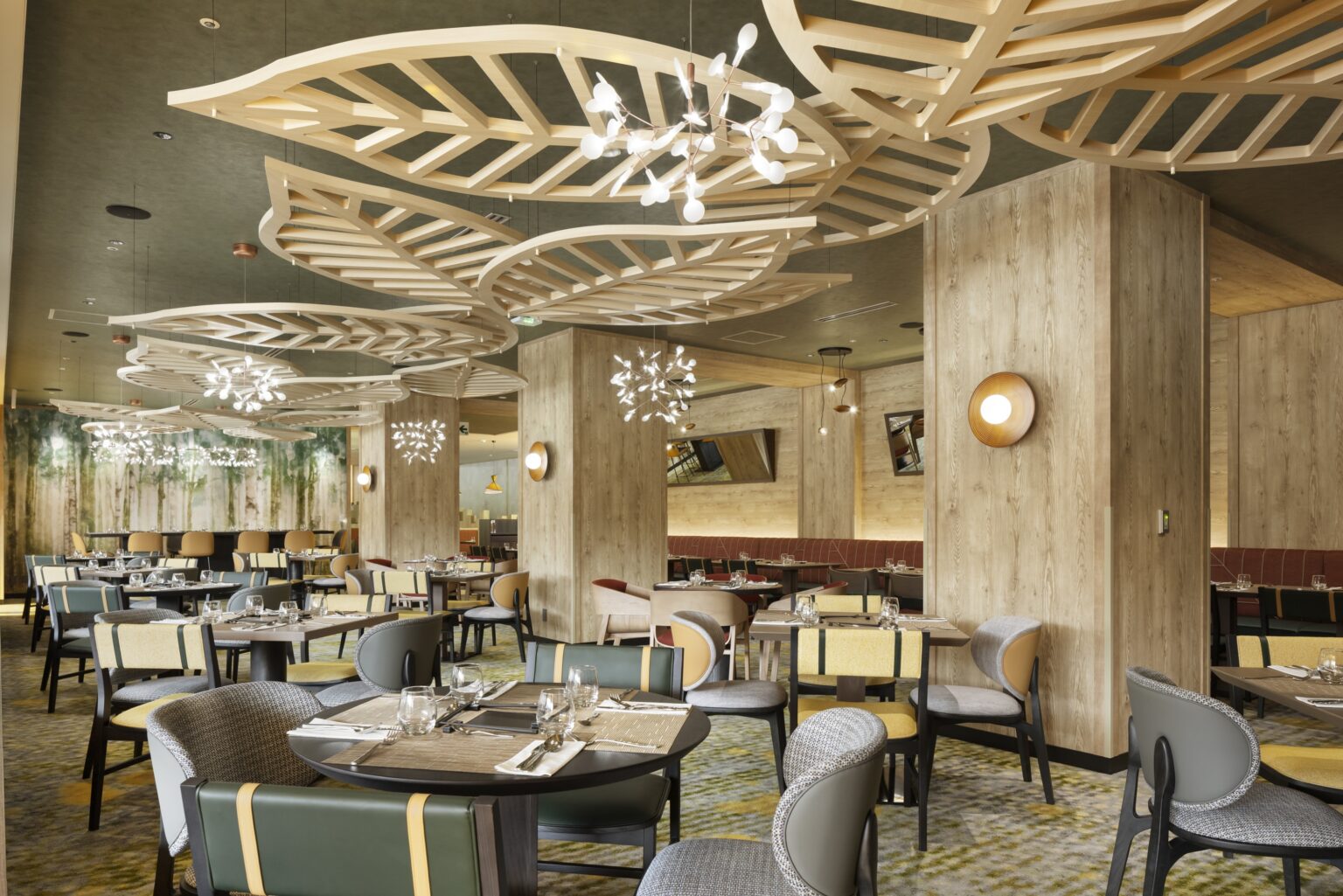 Modern restaurant interior with wooden leaf ceiling design, round tables, and colorful chairs. Soft lighting creates a warm, inviting ambiance.