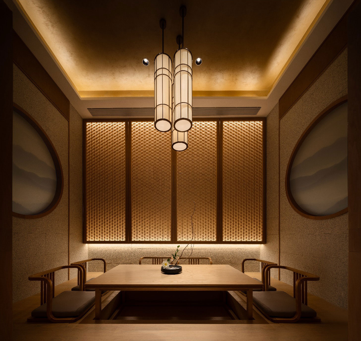 A cozy, minimalist dining room with a wooden table, cushioned chairs, and soft, warm lighting. Japanese decor elements include round wall art and bamboo screens, creating a serene ambiance.