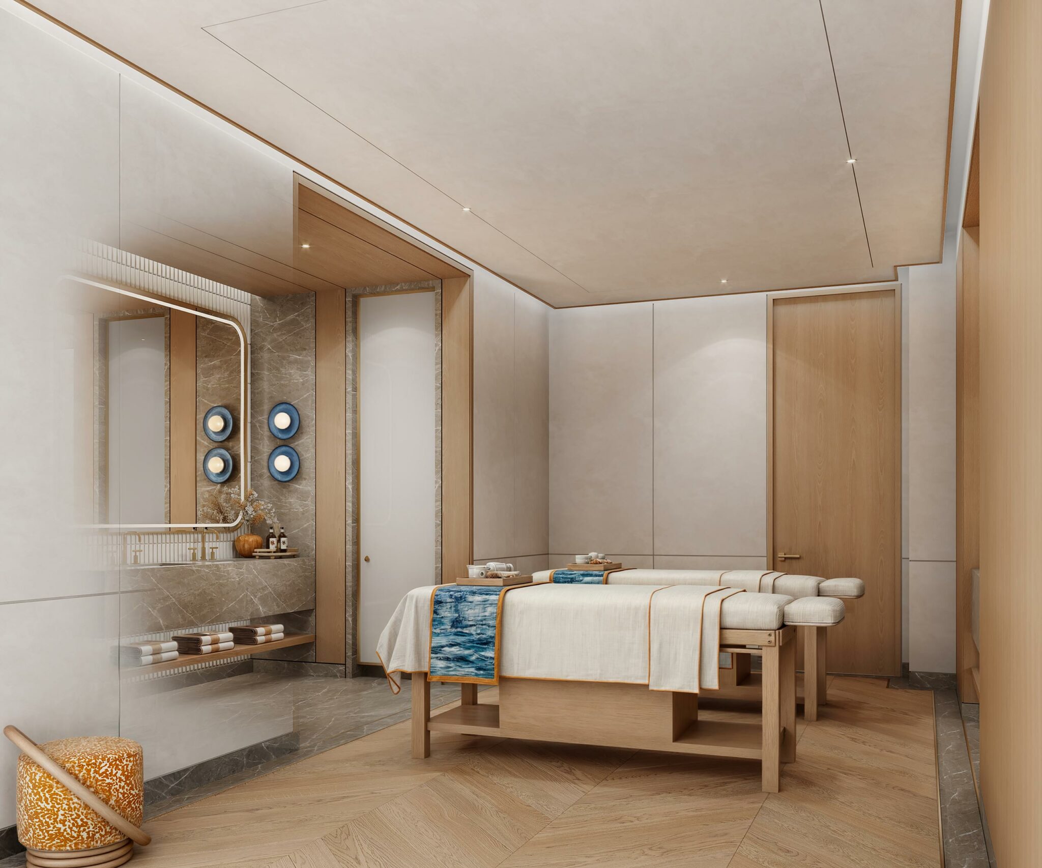 Luxurious spa room with neutral tones featuring two massage tables draped in white and blue linens, wooden elements, soft lighting, and elegant decor.