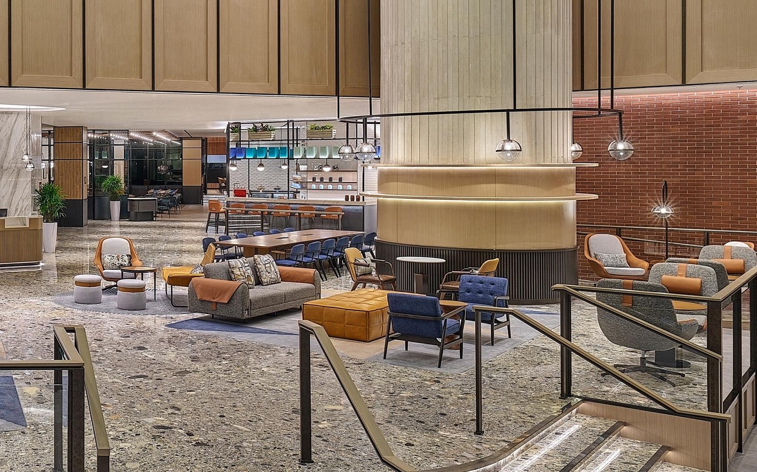 Modern hotel lobby features sleek furnishings, including chairs and sofas in neutral tones. Warm lighting and open layout create an inviting atmosphere.