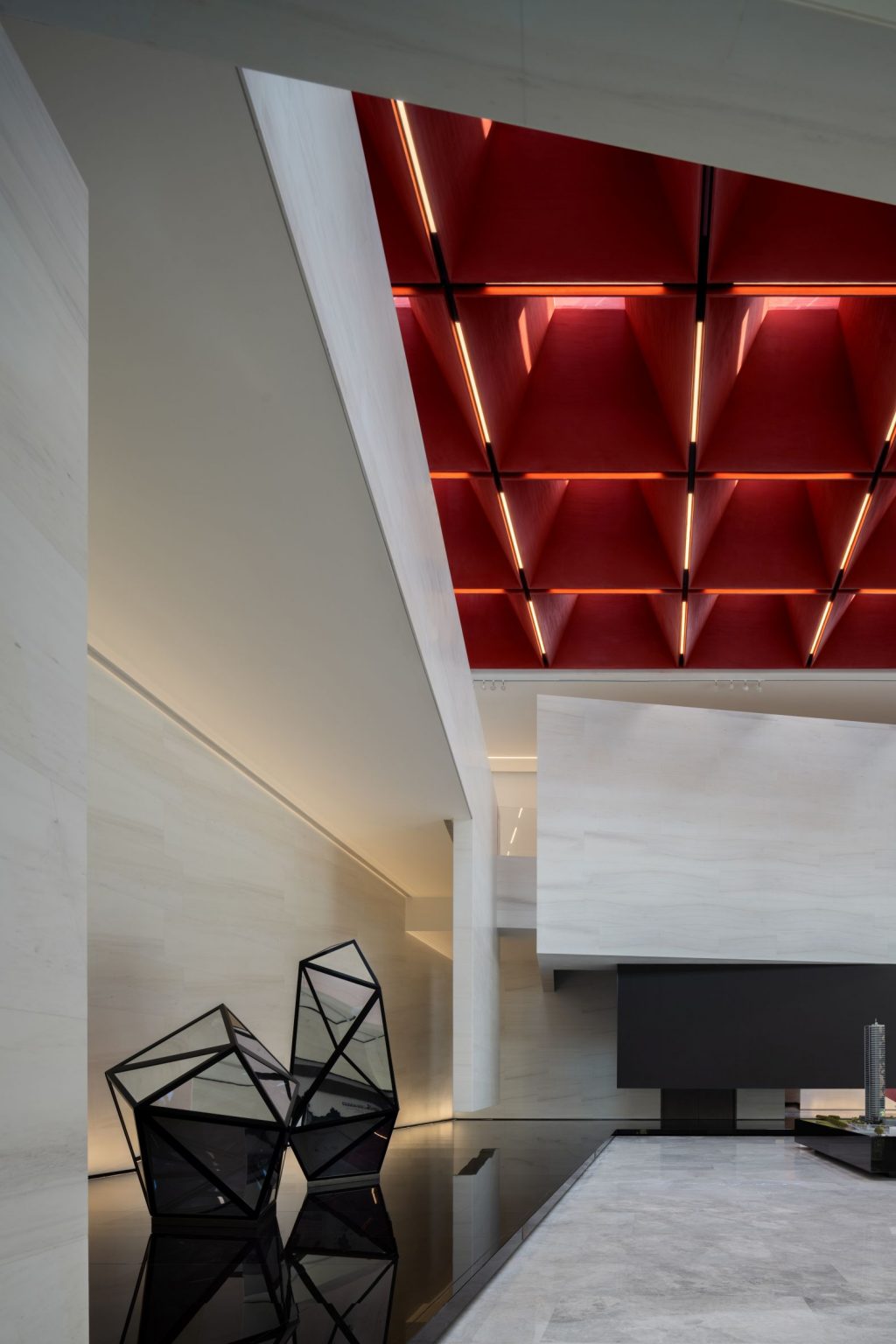 A modern interior design featuring geometric black sculptures, a sleek surface, and a striking red ceiling with linear lighting.