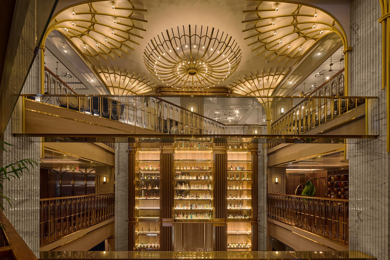Opulent Art Deco hotel interior with gold railings, glowing chandeliers, mirrored balconies, and illuminated liquor shelves creating a glamorous mood.